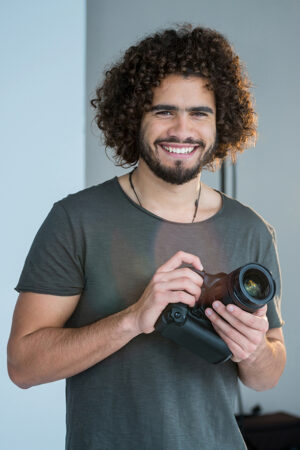 Portrait of happy photographer holding a camera in the studio