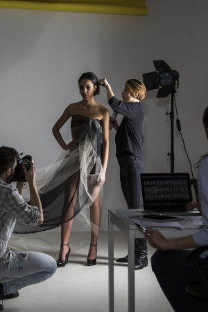 Stylists styling model in low key photography studio shoot